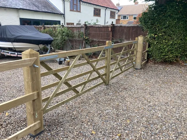 Traditional five-bar timber field gate on a gravel driveway